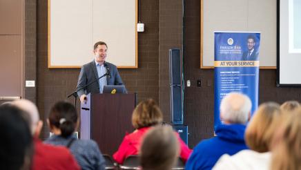 Guest speaker speaking on the podium with crowd in attendance